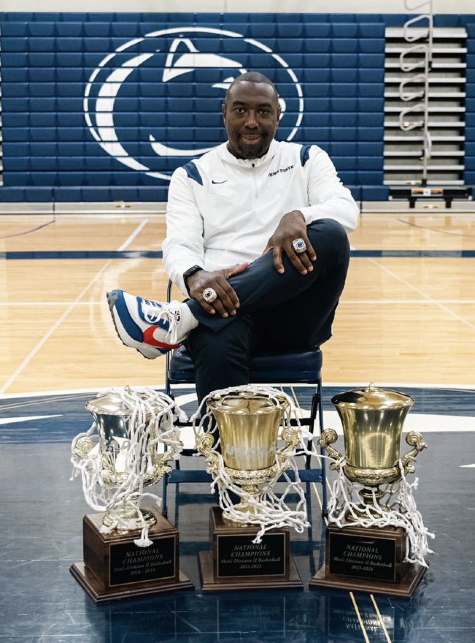 Coach LeShawn R. Hammett seated with his three Men's USCAA Division 2 National Championship trophies